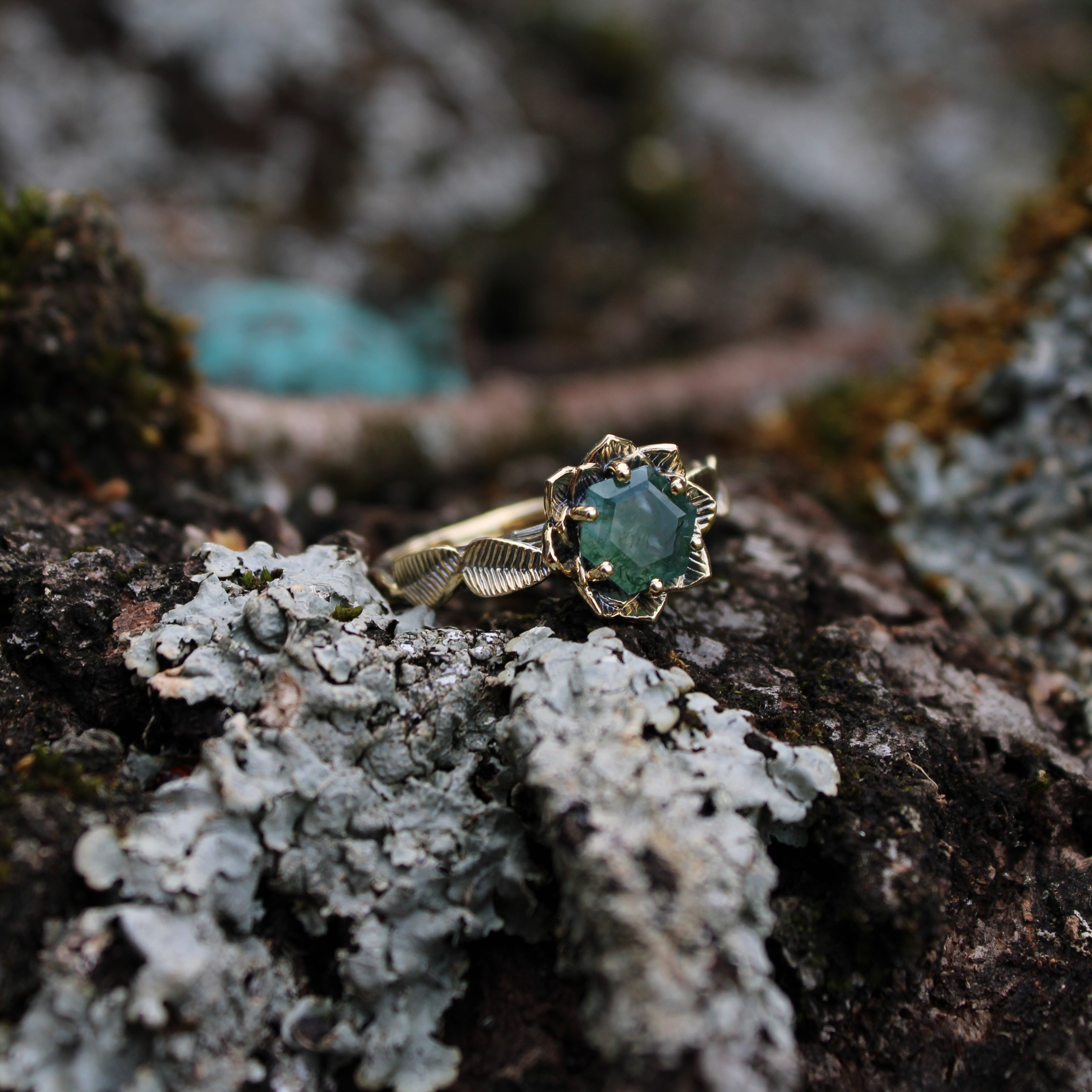 Gold Lotus ring with a green Moss Agate gemstone on a textured surface