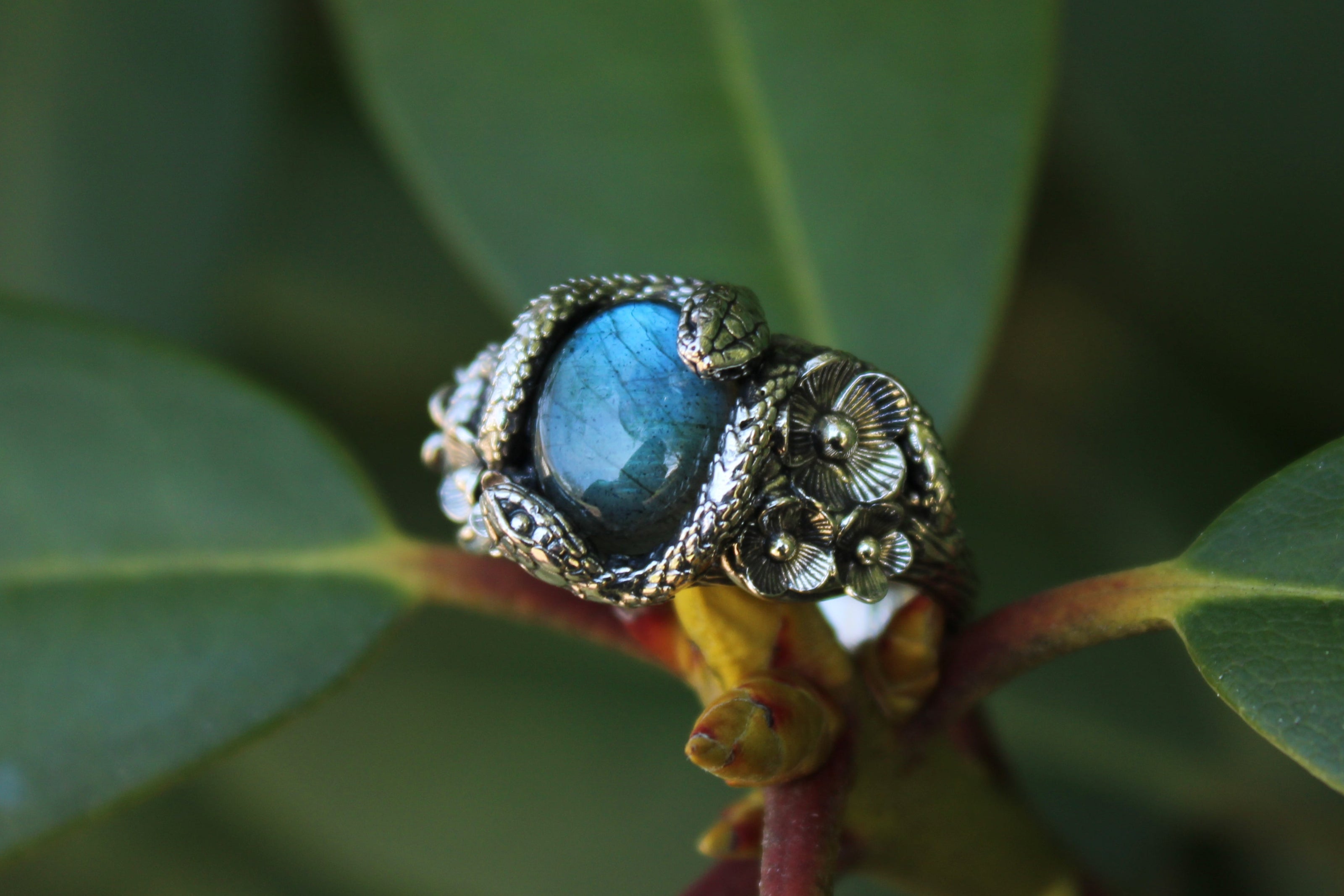 Snake Ring with a Labradorite gemstone on a branch with green leaves